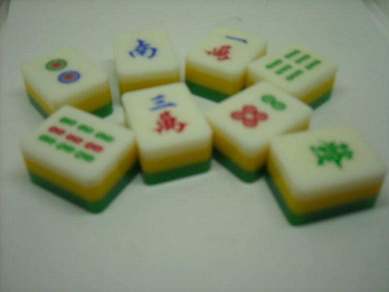 May include: A set of nine colorful mahjong tiles with Chinese characters and symbols. The tiles are arranged in a semi-circle on a white surface.