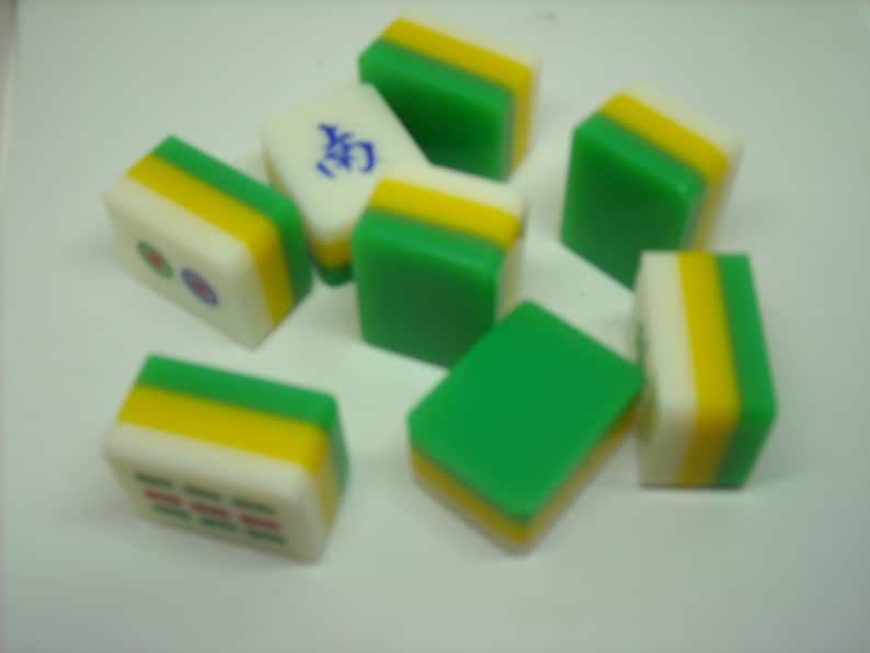 May include: A set of ten green, yellow, and white mahjong tiles. The tiles have Chinese characters and symbols on them.