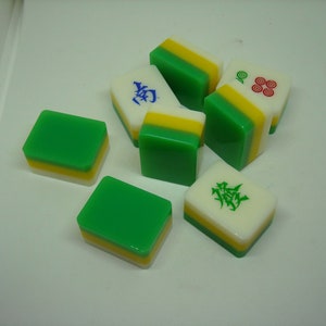 May include: A set of six green, yellow, and white mahjong tiles. The tiles have different Chinese characters and symbols on them.