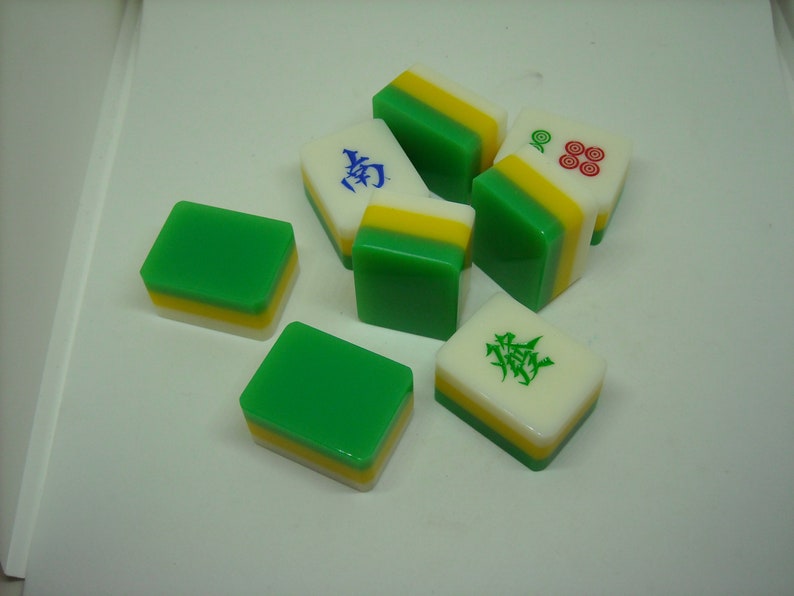 May include: A set of six green, yellow, and white mahjong tiles. The tiles have different Chinese characters and symbols on them.