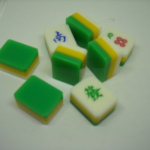 May include: A set of six green, yellow, and white mahjong tiles. The tiles have Chinese characters and a flower design.