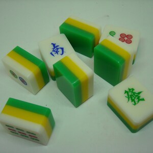 May include: A set of nine green, yellow, and white mahjong tiles. The tiles have Chinese characters and symbols on them.
