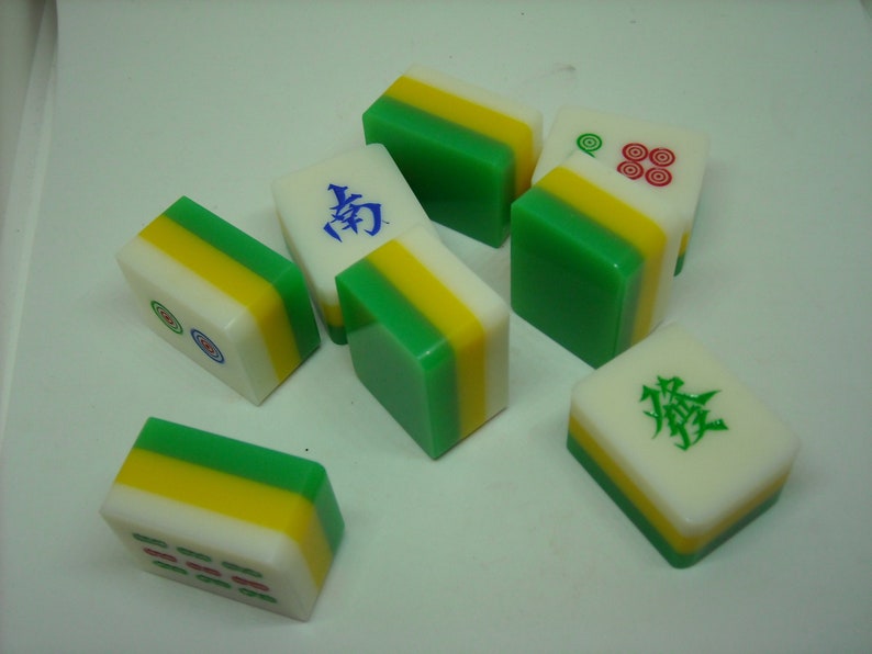 May include: A set of nine green, yellow, and white mahjong tiles. The tiles have Chinese characters and symbols on them.