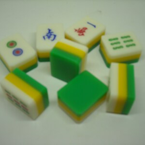 May include: A set of eight green, yellow, and white mahjong tiles. The tiles have Chinese characters and symbols on them.