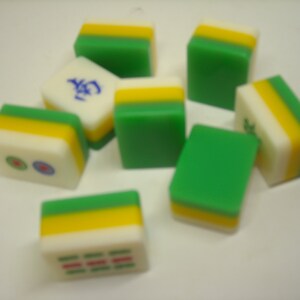 May include: A set of nine green, yellow, and white mahjong tiles. The tiles have Chinese characters and symbols on them.