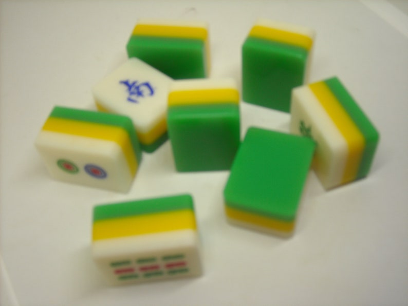 May include: A set of nine green, yellow, and white mahjong tiles. The tiles have Chinese characters and symbols on them.