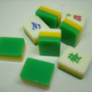May include: A set of six green, white, and yellow mahjong tiles. The tiles have different Chinese characters and symbols on them.