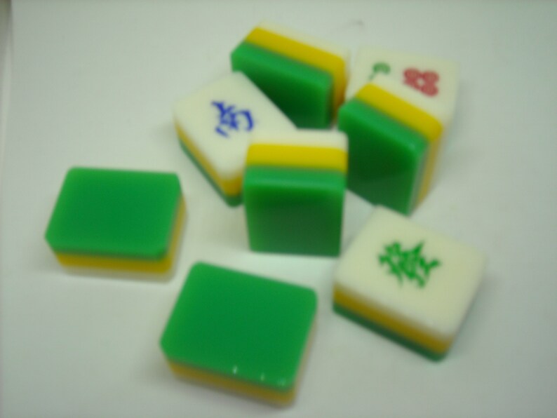May include: A set of six green, white, and yellow mahjong tiles. The tiles have different Chinese characters and symbols on them.