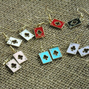 May include: A set of 10 pairs of gold-tone earrings featuring a playing card design. Each earring features a different colored card with a black clover symbol. The cards are red, white, pink, blue, and black.