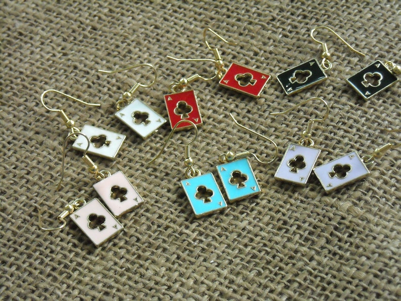 May include: A set of 10 pairs of gold-tone earrings featuring a playing card design. Each earring features a different colored card with a black clover symbol. The cards are red, white, pink, blue, and black.