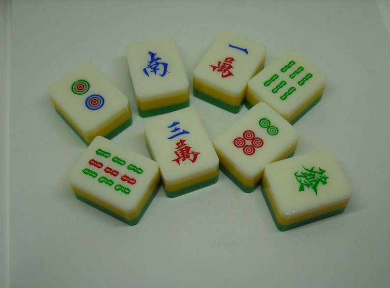 May include: A set of nine Chinese dominoes, also known as mahjong tiles. The tiles are white with green, red, and blue markings. Some tiles have Chinese characters, while others have dots or lines.