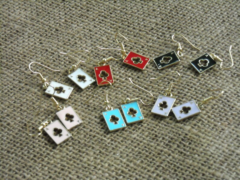 May include: A set of 10 pairs of earrings featuring a playing card design. The earrings are made of gold-tone metal and feature a variety of colors, including red, black, white, blue, and pink. Each earring features a different playing card suit, including clubs, diamonds, hearts, and spades.