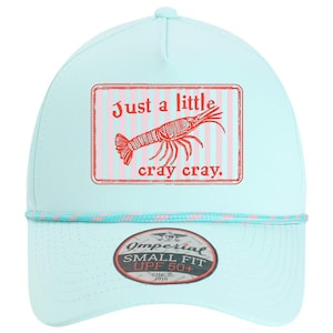 May include: A light blue baseball cap with a shrimp graphic and the text "Just a little cray cray." The cap has a small fit and UPF 50+ protection.