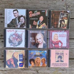 Puede incluir: Una colección de nueve CD de música country con artistas como Patsy Cline, George Jones, Loretta Lynn, Kenny Rogers, Dolly Parton y Tammy Wynette. Las portadas de los álbumes muestran varios retratos y títulos como 12 Greatest Hits, 16 Biggest Hits, A Holly Dolly Christmas y Honky Tonk Angels.