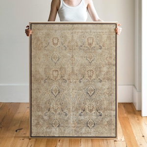 May include: A large rectangular framed artwork featuring a detailed, vintage-style rug design. The rug has a beige and brown color palette with intricate floral and geometric patterns. The artwork is held up against a neutral background.