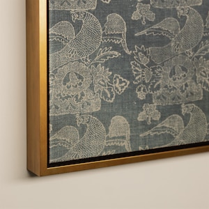 May include: A framed canvas print featuring a repeating pattern of stylized birds and floral elements in off-white against a muted blue background. The artwork is encased in a gold-colored frame, adding a touch of elegance to the design.