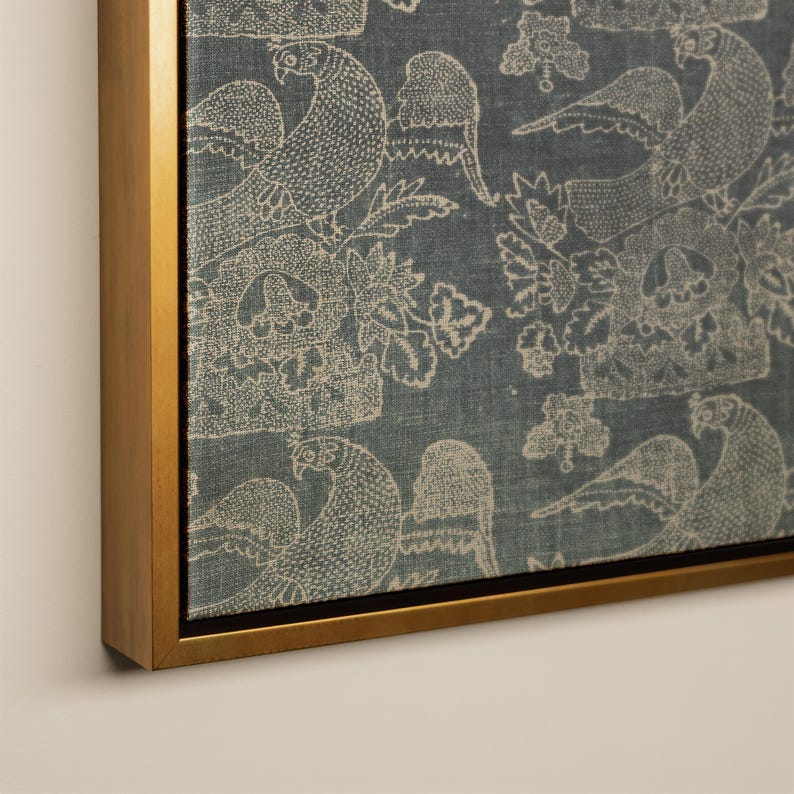 May include: A framed canvas print featuring a repeating pattern of stylized birds and floral elements in off-white against a muted blue background. The artwork is encased in a gold-colored frame, adding a touch of elegance to the design.