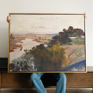 May include: A landscape painting in a gold-coloured frame. The artwork shows a river winding through a valley, with trees and fields in the background. The colour palette includes muted tones of brown, green, and blue.