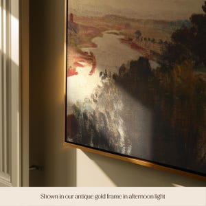 May include: A landscape painting in an antique gold frame. The artwork depicts a river and trees, with a palette of browns, reds, and golds. The text at the bottom reads "Shown in our antique gold frame in afternoon light."