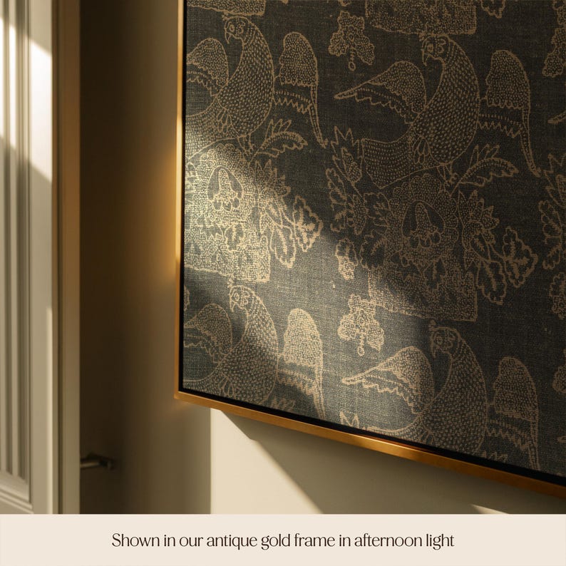 May include: A framed artwork featuring a repeating pattern of stylized birds and floral elements in gold against a dark teal background. The artwork is displayed in a gold frame, creating a luxurious aesthetic. The text at the bottom reads "Shown in our antique gold frame in afternoon light."