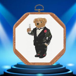 Può includere: Un orso marrone che indossa uno smoking nero e tiene un bicchiere di champagne. L'orso è incorniciato in un ottagono di legno.