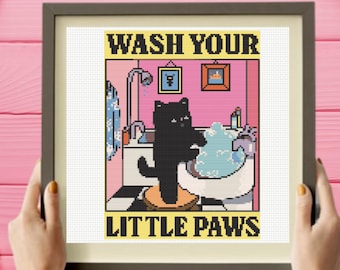 Könnte beinhalten: Ein gerahmtes Kreuzstichmuster mit einer schwarzen Katze, die auf einem Hocker in einem rosa Badezimmer steht und ihre Pfoten in einem mit blauen Blasen gefüllten Waschbecken wäscht. Der Text WASH YOUR LITTLE PAWS steht in schwarzen Buchstaben auf gelbem Grund.