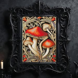 May include: A rectangular cross-stitch embroidery featuring three mushrooms with vibrant red caps and cream-colored stems, surrounded by intricate beige and grey foliage patterns, encased in a detailed, ornate black frame with scrollwork.