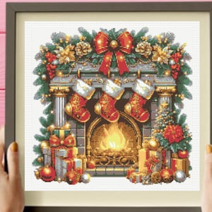 Puede incluir: Un patrón de punto de cruz enmarcado que representa una chimenea con fuego, tres calcetines navideños rojos y dorados colgados de la repisa, un lazo rojo grande, guirnaldas de pino, regalos envueltos y adornos en una escena festiva.