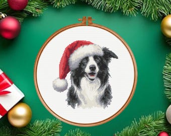 Puede incluir: Un patrón de punto de cruz que muestra un perro Border Collie blanco y negro con un gorro de Papá Noel rojo y blanco, exhibido dentro de un bastidor de bordado circular de madera sobre un fondo de tela blanca.