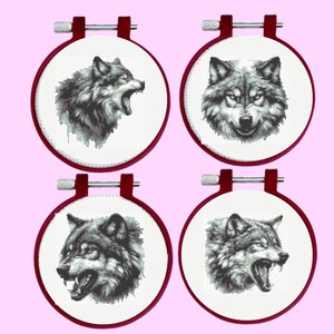 May include: Four circular embroidery hoops with dark red frames, each containing white fabric featuring a detailed black and white cross-stitch portrait of a wolf head. The wolves are depicted in various expressions, including snarling and facing forward.