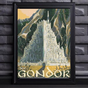May include: A framed cross-stitch embroidery depicting a white multi-tiered castle structure set against dark green mountains and a pale yellow sky. The word GONDOR is stitched in white capital letters at the bottom of the rectangular artwork.