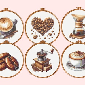 May include: Six circular wooden embroidery hoops containing cross-stitch patterns of coffee-themed imagery, including a latte with heart art, a heart-shaped arrangement of coffee beans, a glass pour-over brewer, coffee beans, a manual grinder, and a cappuccino.