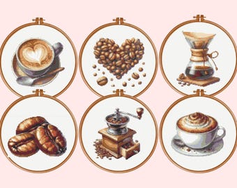 May include: Six circular wooden embroidery hoops containing cross-stitch patterns of coffee-themed imagery, including a latte with heart art, a heart-shaped arrangement of coffee beans, a glass pour-over brewer, coffee beans, a manual grinder, and a cappuccino.