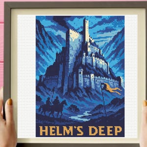 Puede incluir: Un patrón de punto de cruz enmarcado con una ilustración pixelada de una fortaleza en las montañas. La escena utiliza tonos azules y negros, con una bandera amarilla y el texto HELM'S DEEP en amarillo en la parte inferior del diseño.