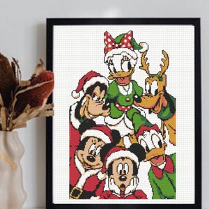 Könnte beinhalten: Ein gerahmtes Kreuzstichmuster mit einer Gruppe von Zeichentrickfiguren in weihnachtlicher Kleidung, darunter Weihnachtsmützen und festliche Outfits. Das Design zeigt Mickey Maus, Minnie Maus, Donald Duck, Daisy Duck, Goofy und Pluto.