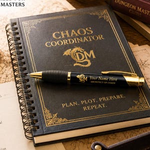 以下が含まれることがあります： CHAOS COORDINATORおよびPLAN. PLOT. PREPARE. REPEAT.と金色の箔押し文字が施された黒いスパイラルノート。表紙の上には、Your Name HereおよびARCHITECT OF CHAOSという文字が刻まれた黒と金のボールペンが置かれています。