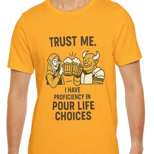 May include: Mustard yellow t-shirt with the text "TRUST ME." above an illustration of two fantasy characters toasting beer mugs. Below the illustration, the text reads "I HAVE PROFICIENCY IN POUR LIFE CHOICES."