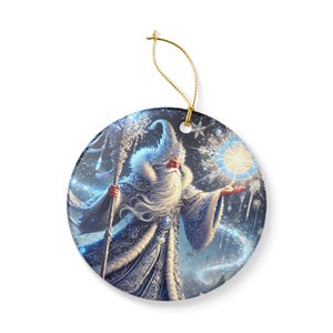Op de afbeelding: Ronde kerstversiering met een wintertovenaar met een lange witte baard, die een staf en een gloeiende bol vasthoudt. De tovenaar draagt een blauw-witte jurk met ingewikkelde patronen. Een gouden draad is bevestigd om op te hangen.