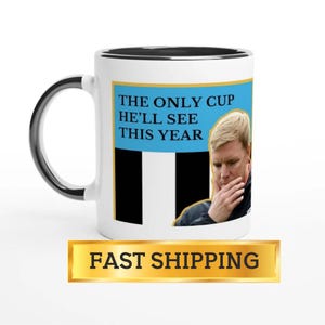 Puede incluir: Taza de cer&aacute;mica blanca con asa y borde negros. La taza presenta un rect&aacute;ngulo azul con el texto "THE ONLY CUP HE'LL SEE THIS YEAR" y una imagen de un hombre. La taza tiene un borde dorado.