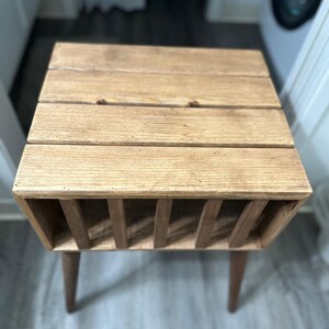 May include: A wooden side table with a slatted top and a shelf underneath. The table has a natural wood finish and is supported by four legs.
