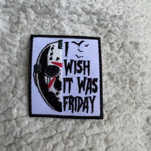 May include: Square patch with a black border featuring a hockey mask design on the left and the text "I WISH IT WAS FRIDAY" in black on the right. The mask is black, white, and red.