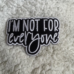 May include: A black and white embroidered patch with the text "I'M NOT FOR everyone". The patch has a black background with white lettering and a white border. The patch is rectangular with rounded edges.