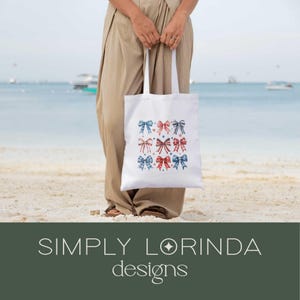 K&ouml;nnte beinhalten: Eine wei&szlig;e Einkaufstasche mit roten, wei&szlig;en und blauen Gingham-Schleifen. Die Tasche tr&auml;gt den Text "SIMPLY LORINDA designs" am Boden.