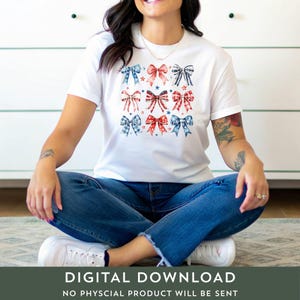 K&ouml;nnte beinhalten: Ein wei&szlig;es T-Shirt mit einem Design aus roten, wei&szlig;en und blauen Schleifen mit Sternen. Die Schleifen sind in einem Rastermuster angeordnet. Das Shirt wird von einer Person getragen.