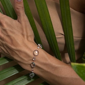 May include: A delicate bracelet featuring a series of clear, round, glass-like beads strung on a thin, transparent cord. The beads vary slightly in size and are spaced out along the length of the cord, creating a floating effect on the wrist.