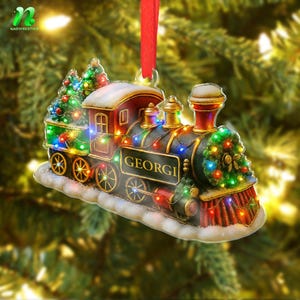 May include: A festive Christmas ornament shaped like a vintage train engine. The ornament is decorated with colorful lights and a small Christmas tree. The name "GEORGI" is displayed on the side. It hangs from a red ribbon.