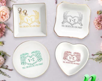 May include: Four white ceramic ring dishes with gold trim. Each dish features a skeleton hand heart design with the text "Y+E" and "TILL DEATH DO US PART" in gold, black, green, and red.