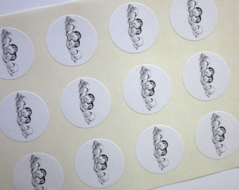 May include: Sheet of white round stickers with black and white illustrations of two babies sleeping. Each sticker has a black and white illustration of two babies sleeping.