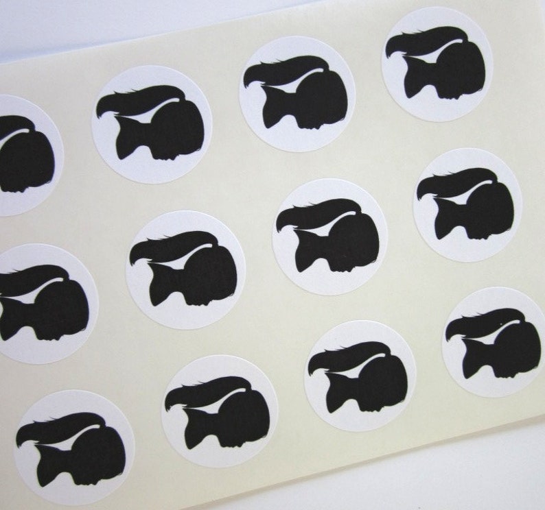 May include: Sheet of white paper with 12 black silhouette stickers of a person with long hair in a ponytail. The stickers are arranged in a grid pattern.