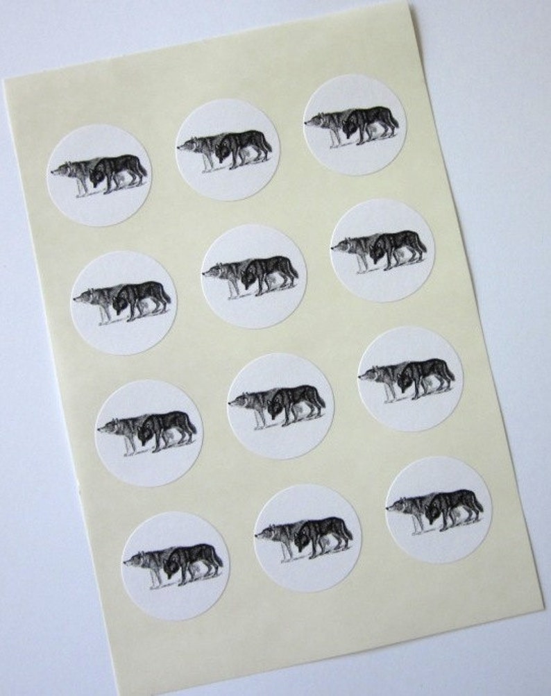 May include: A sheet of white paper with 12 round stickers featuring black and white illustrations of wolves. Each sticker has a wolf walking to the right.